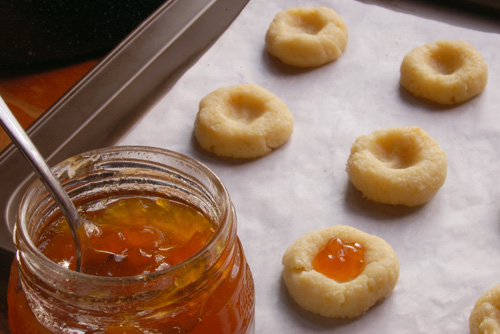 Filling 'thumbprint' cookies with apricot jelly.